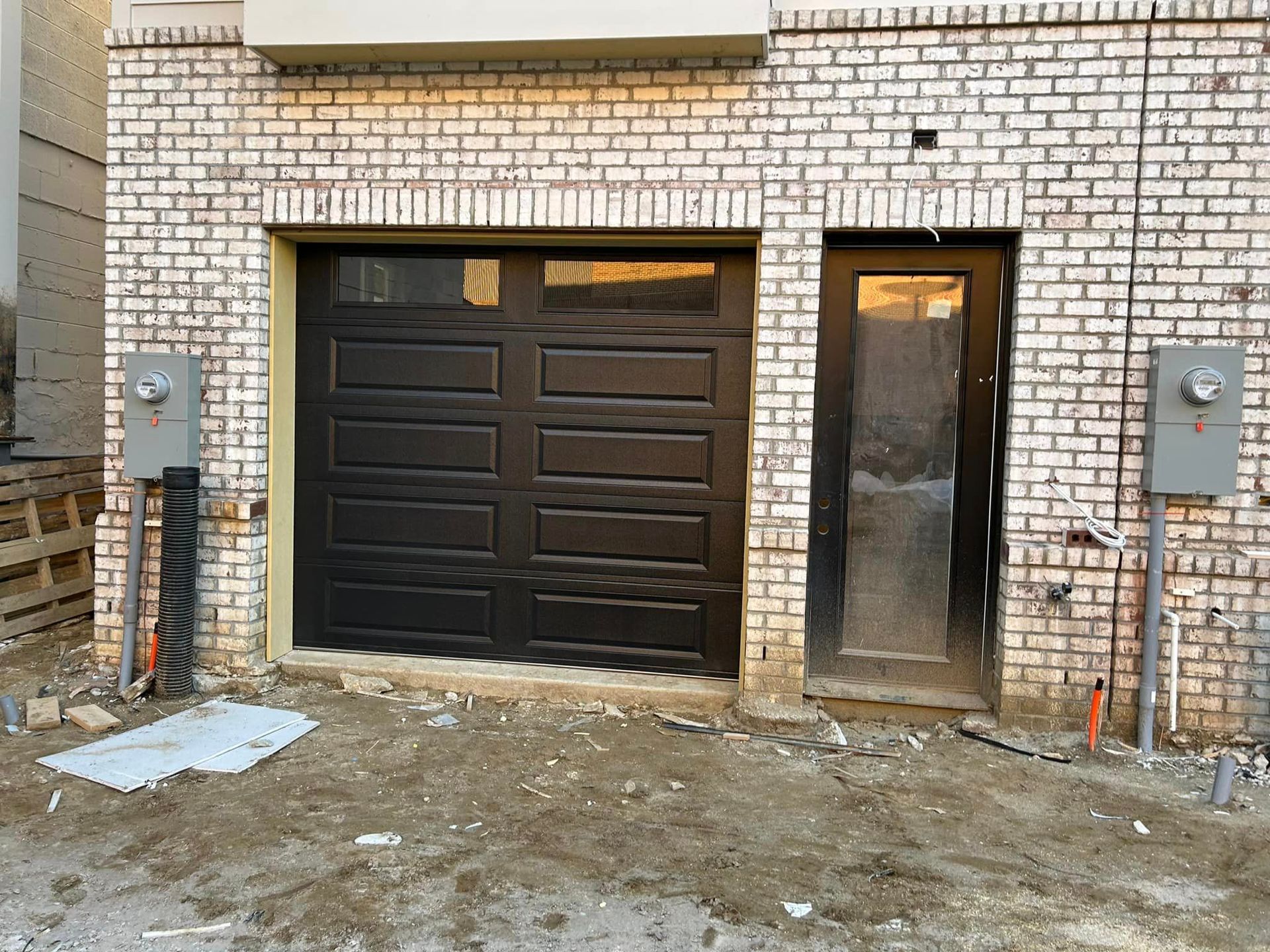 A brick building with a black garage door and a door