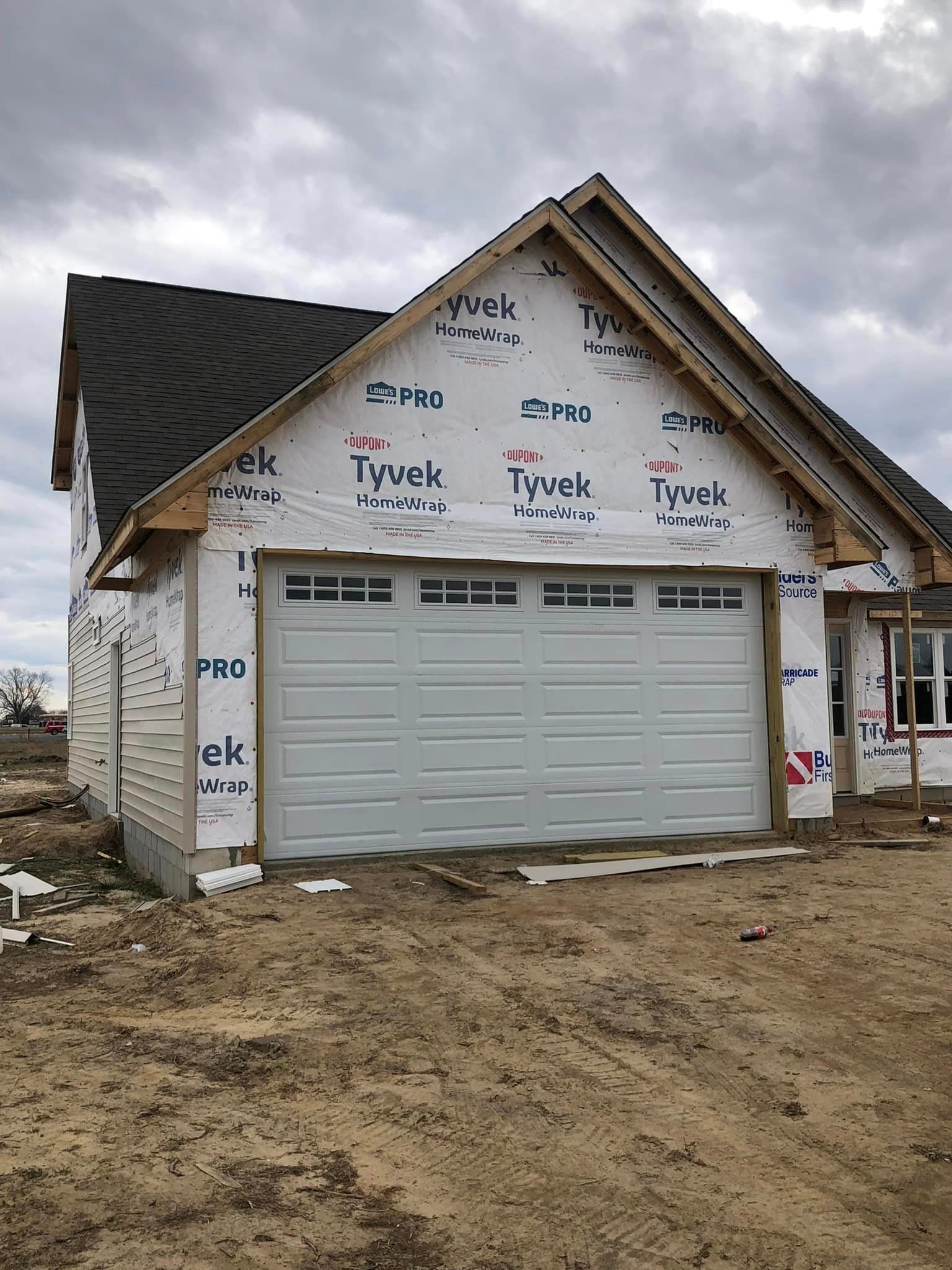 A garage door is being installed on the side of a house under construction.