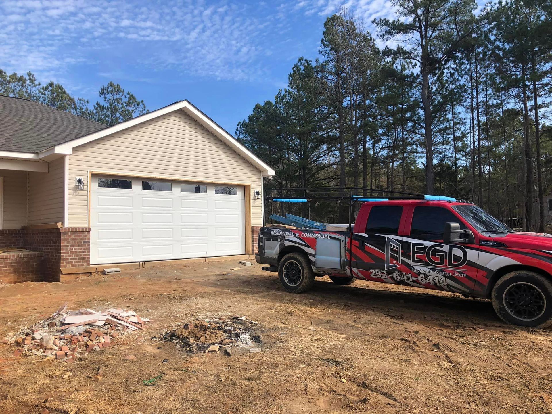 A red truck is parked in front of a garage door.