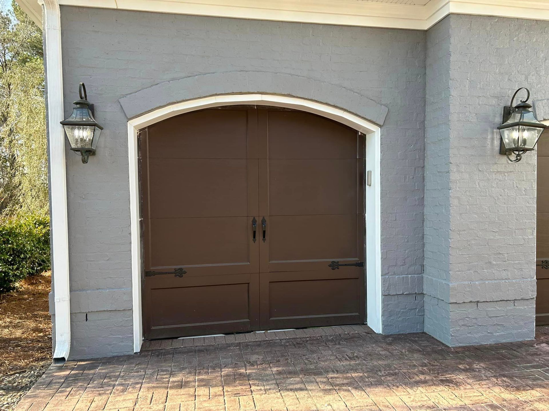 A brown garage door is on the side of a brick building.