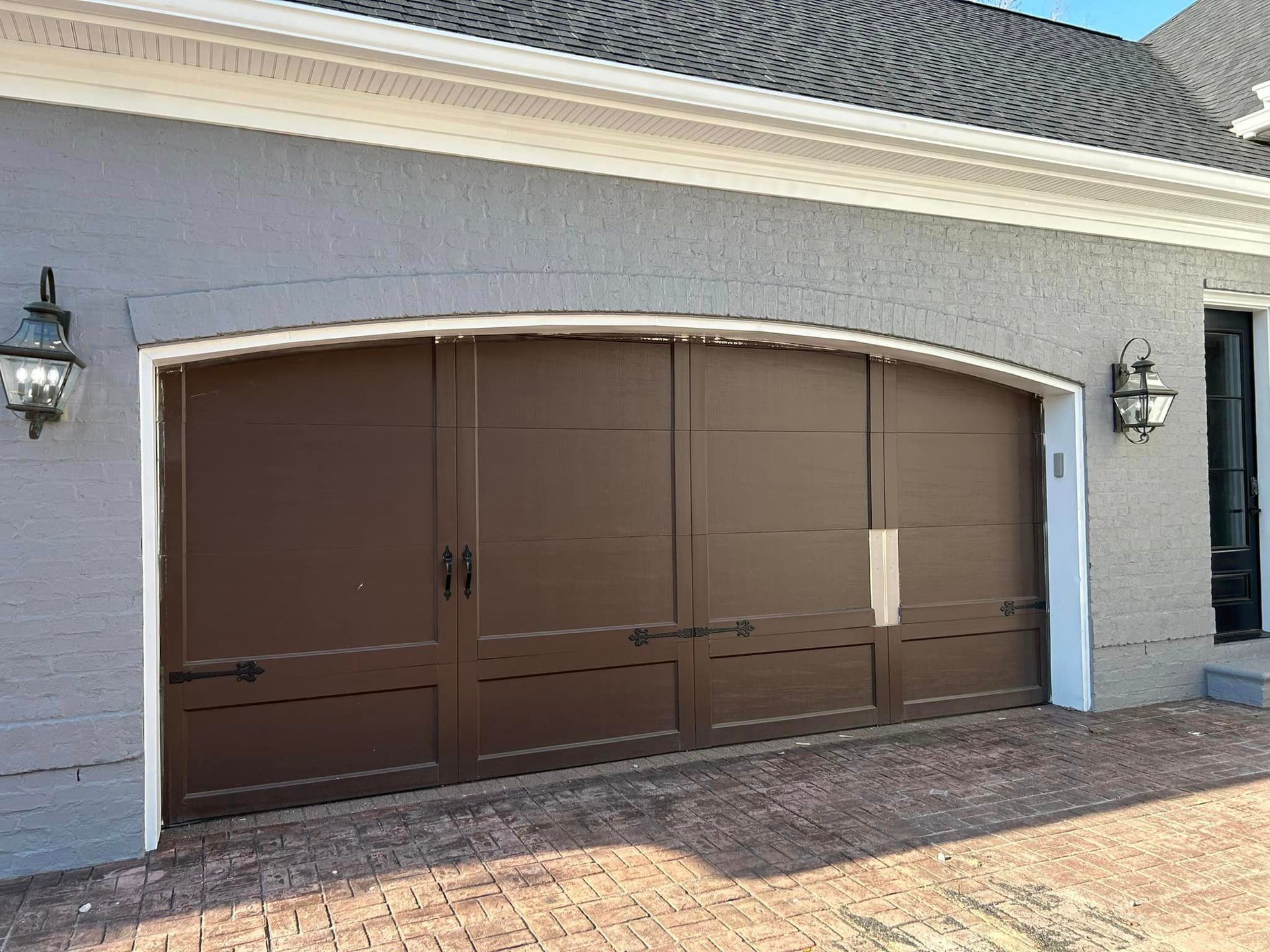 A large brown garage door is on the side of a house.