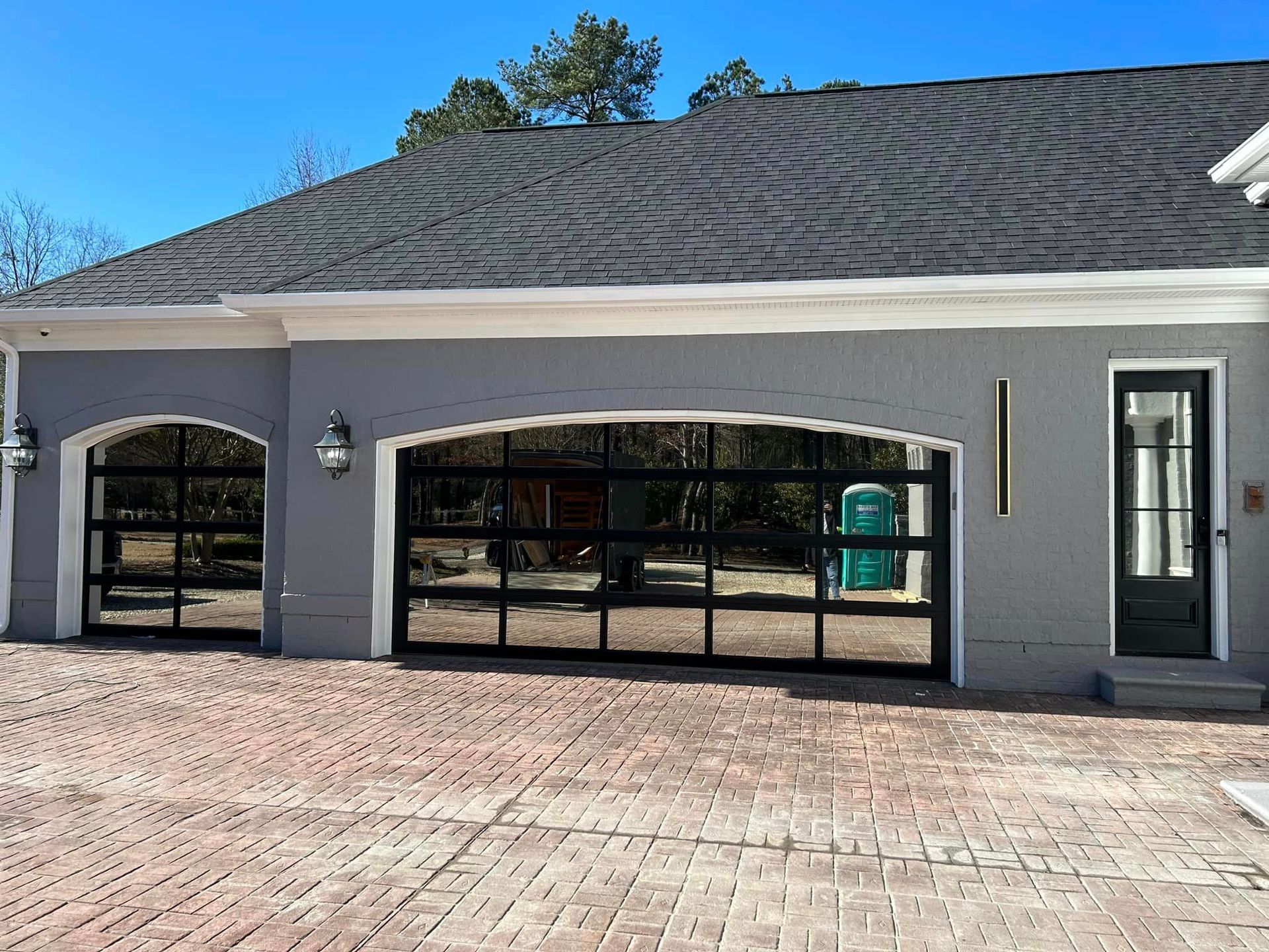 A house with a large garage door and a brick driveway.