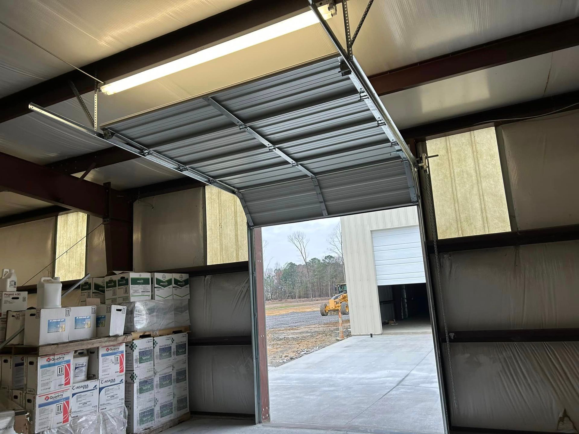 A garage door is open to a warehouse filled with boxes.