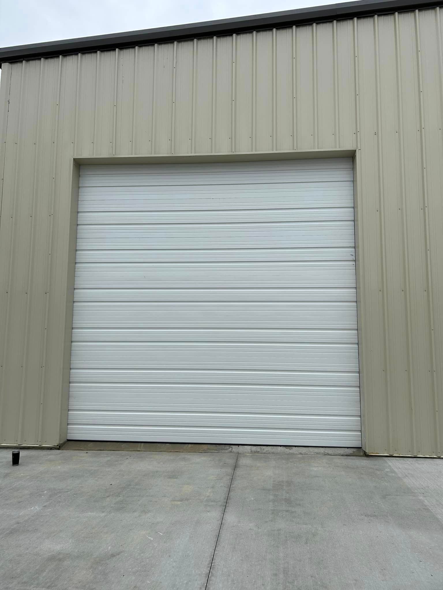 A white garage door is open on the side of a building