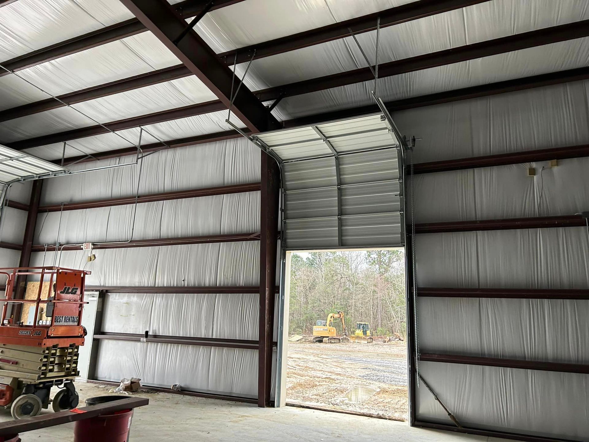 A large metal building with a garage door open.