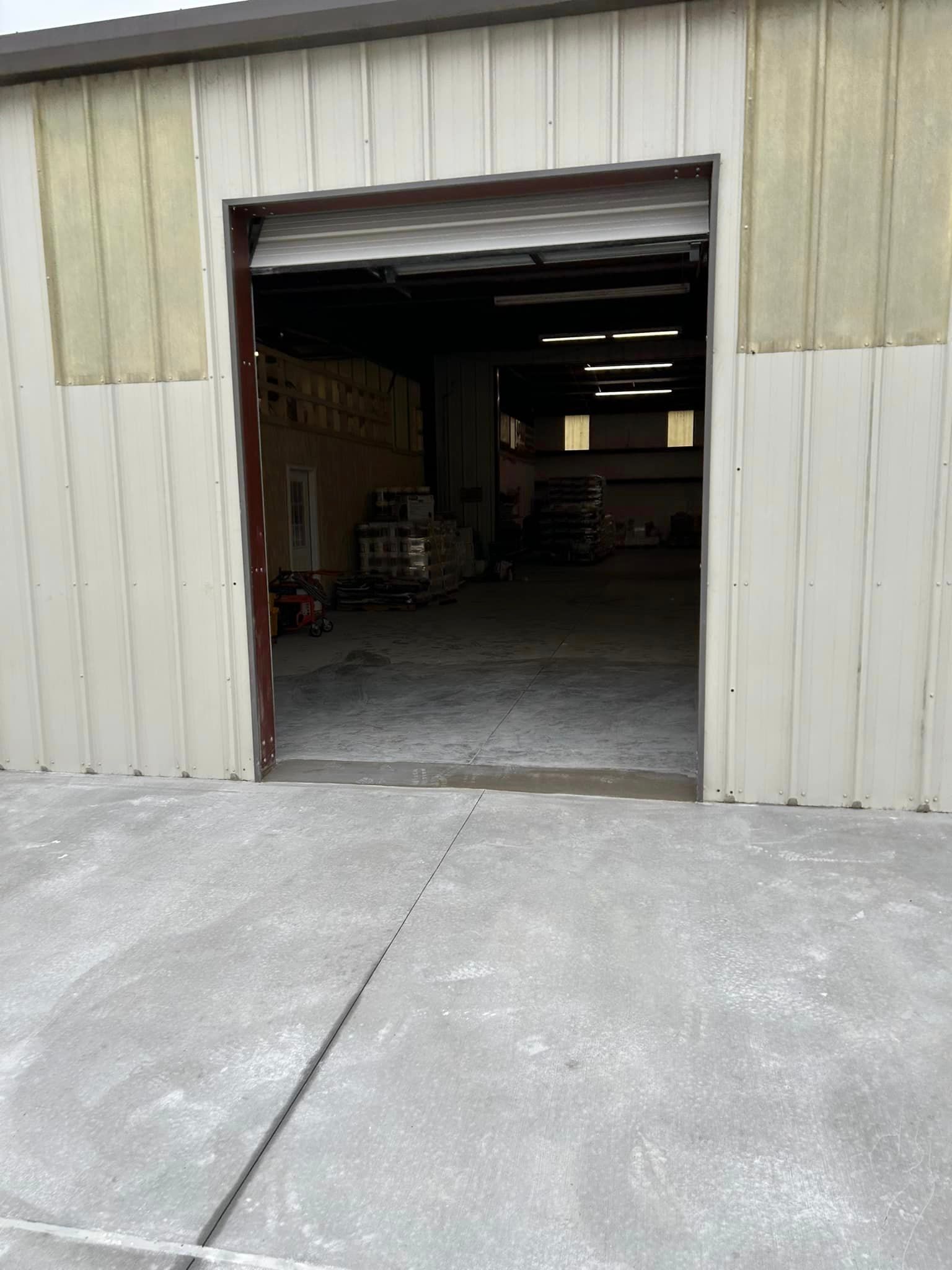 A warehouse with a garage door open and a concrete floor.