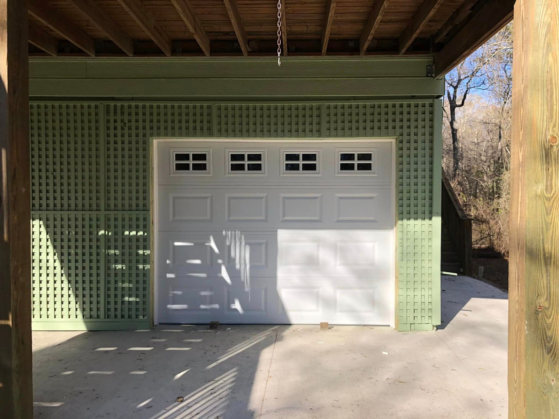 A garage with a white garage door and a green wall.