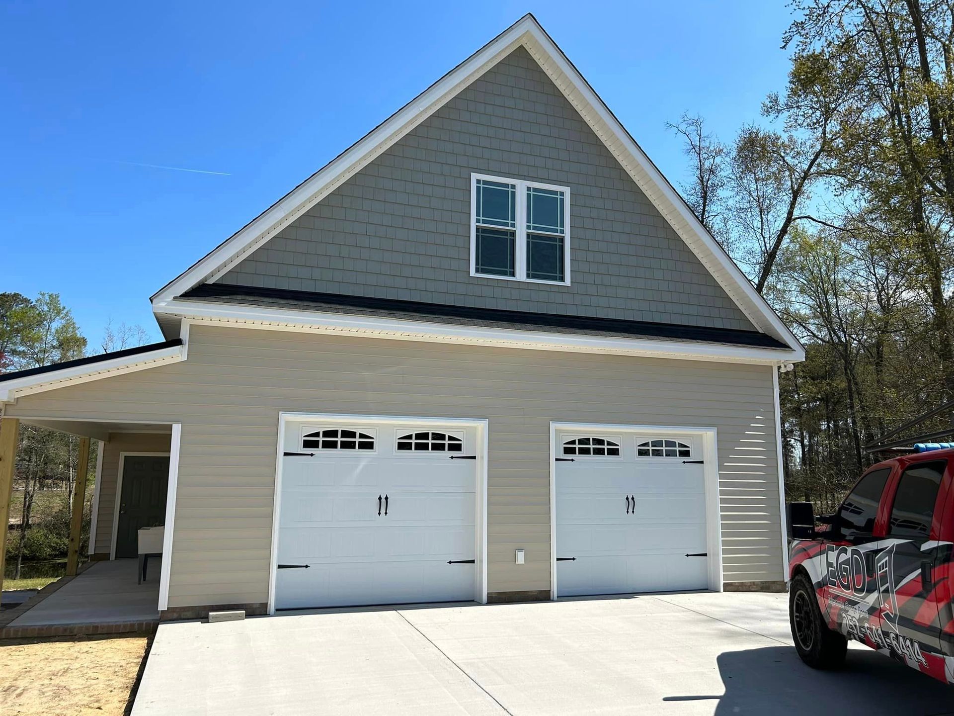A red truck is parked in front of a garage.