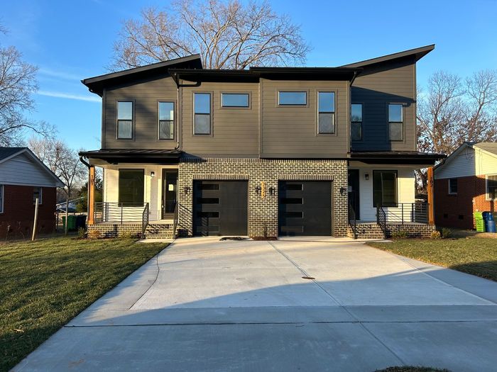 A large house with two garages and a driveway in front of it.