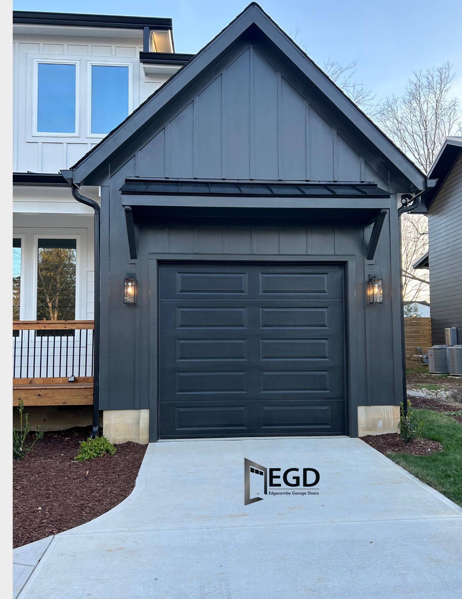A black garage door is in front of a white house