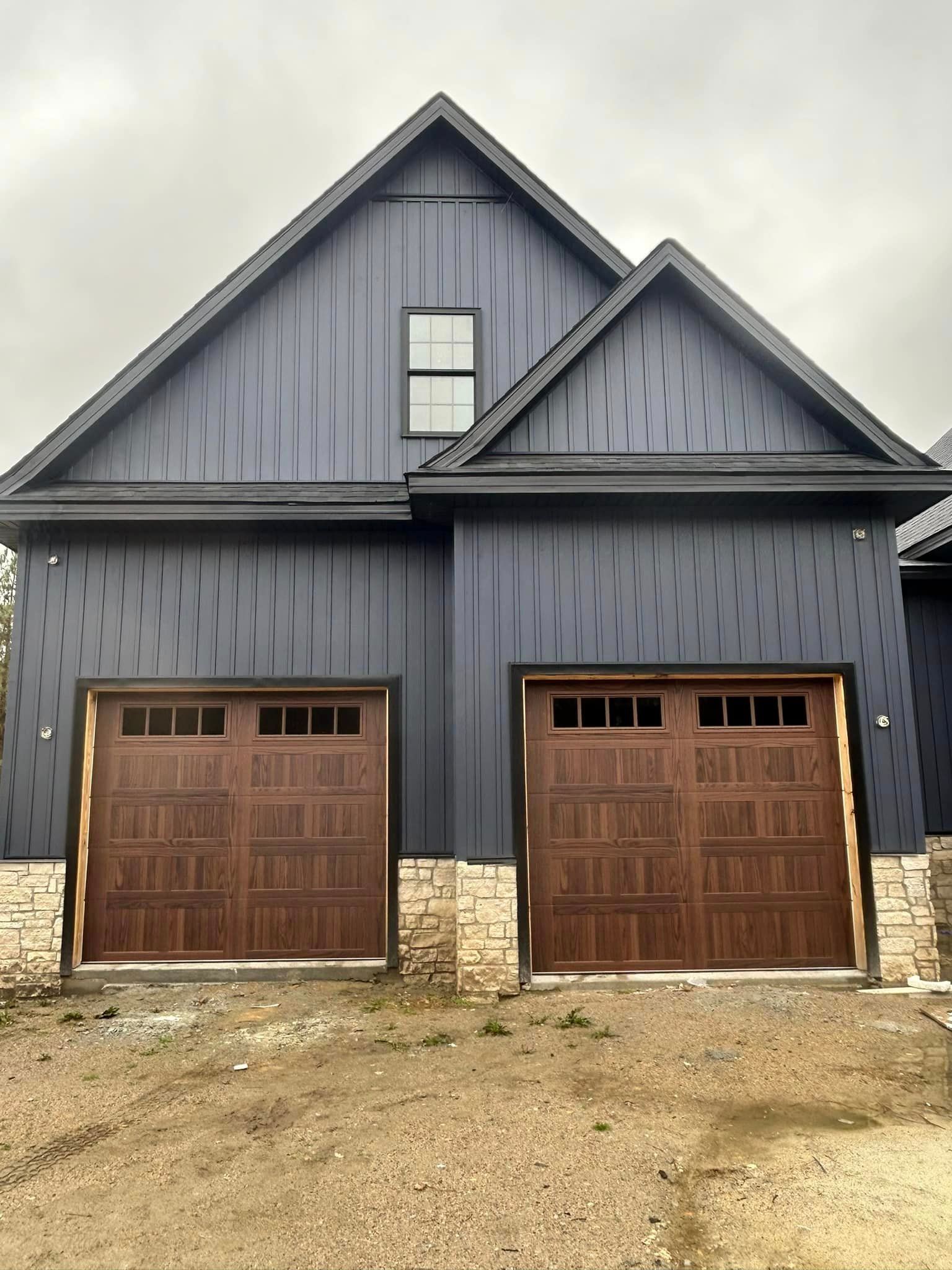There are two garage doors on the side of a house.