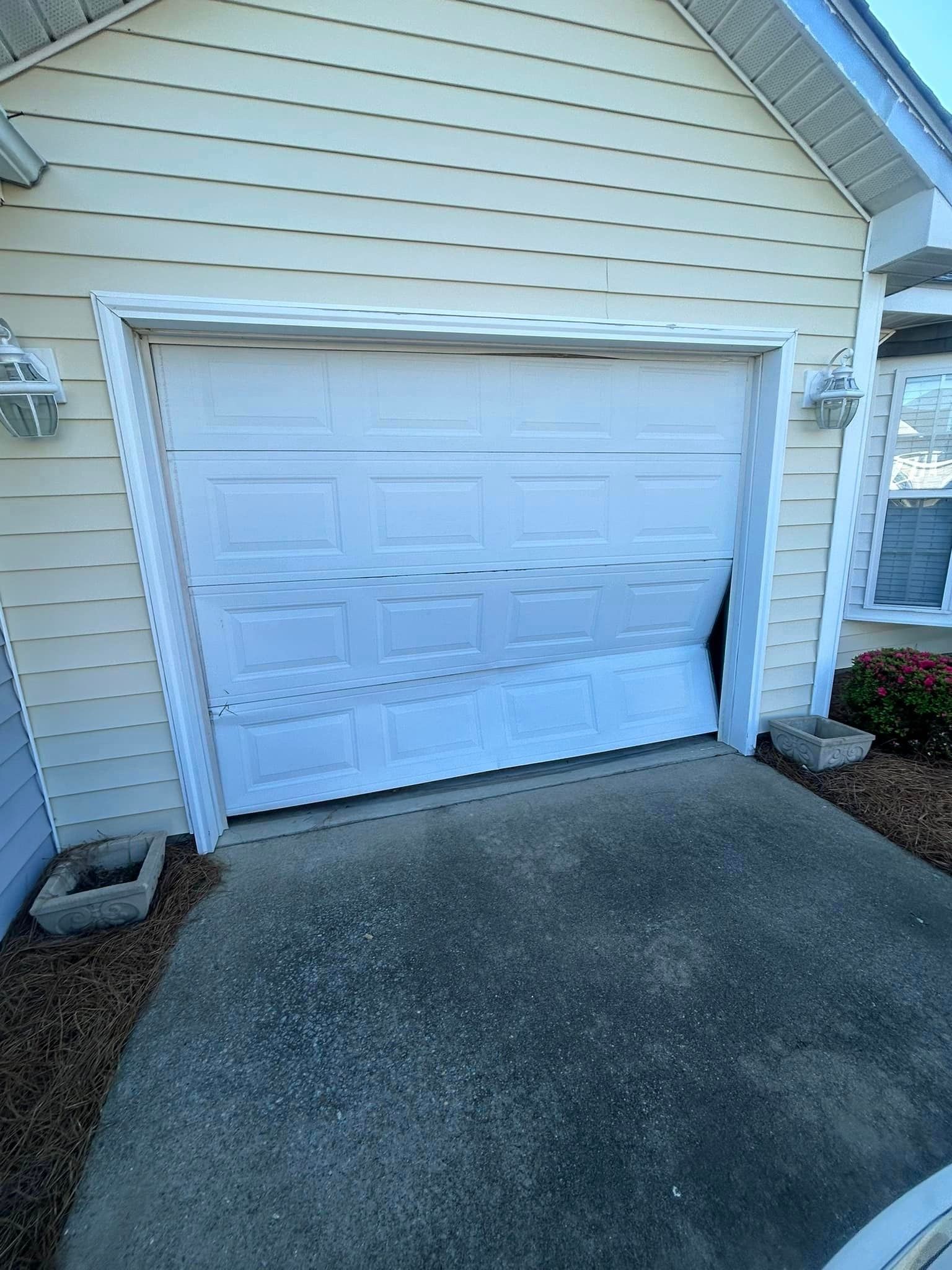A white garage door is open on the side of a house.