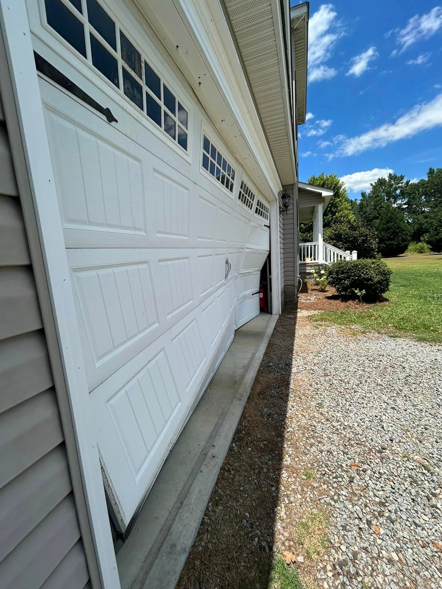 A white garage door is sitting on the side of a house.