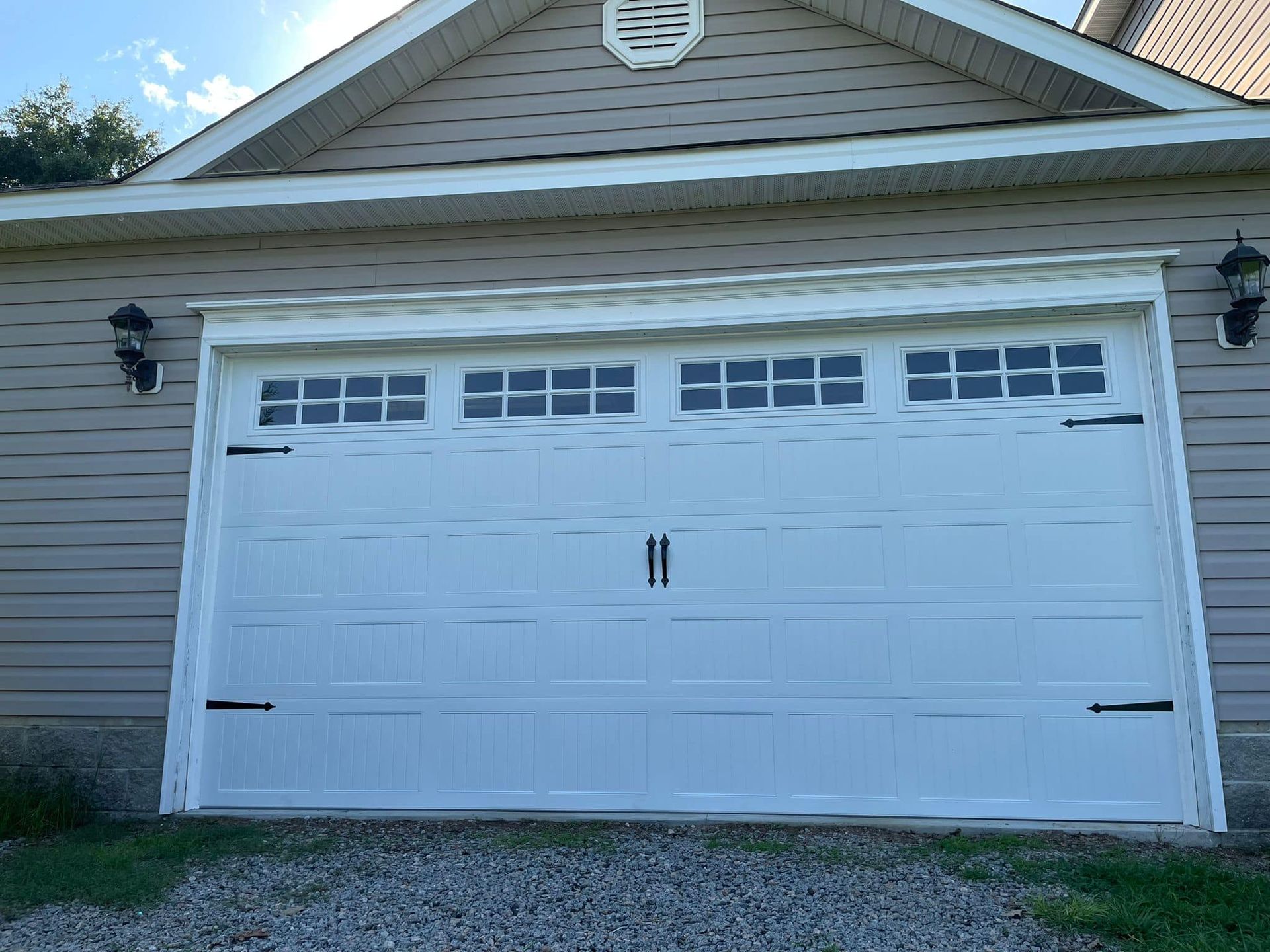 A white garage door is sitting in front of a house.
