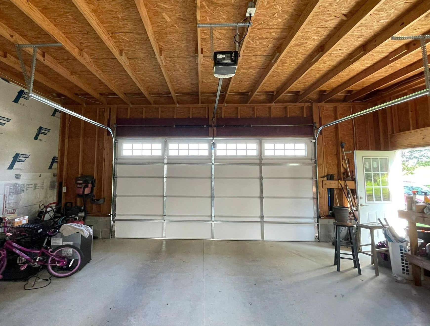 A garage with a garage door open and a bicycle in it.