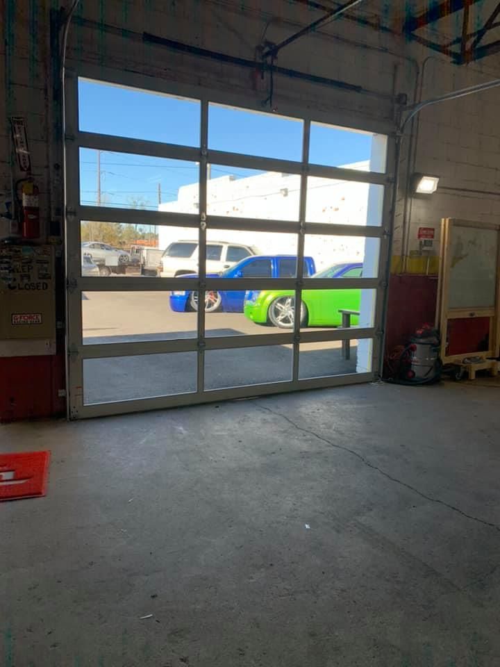 A garage with a green car parked in front of a garage door.