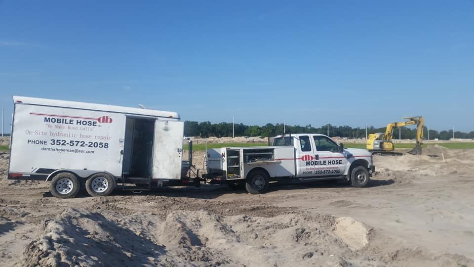 Truck towing a trailer on a construction site. An excavator works in the background. Bright sunny day.