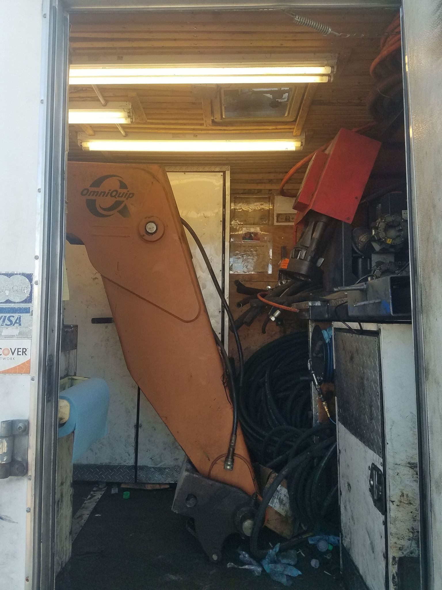 Inside of a truck, an orange excavator arm is surrounded by equipment.