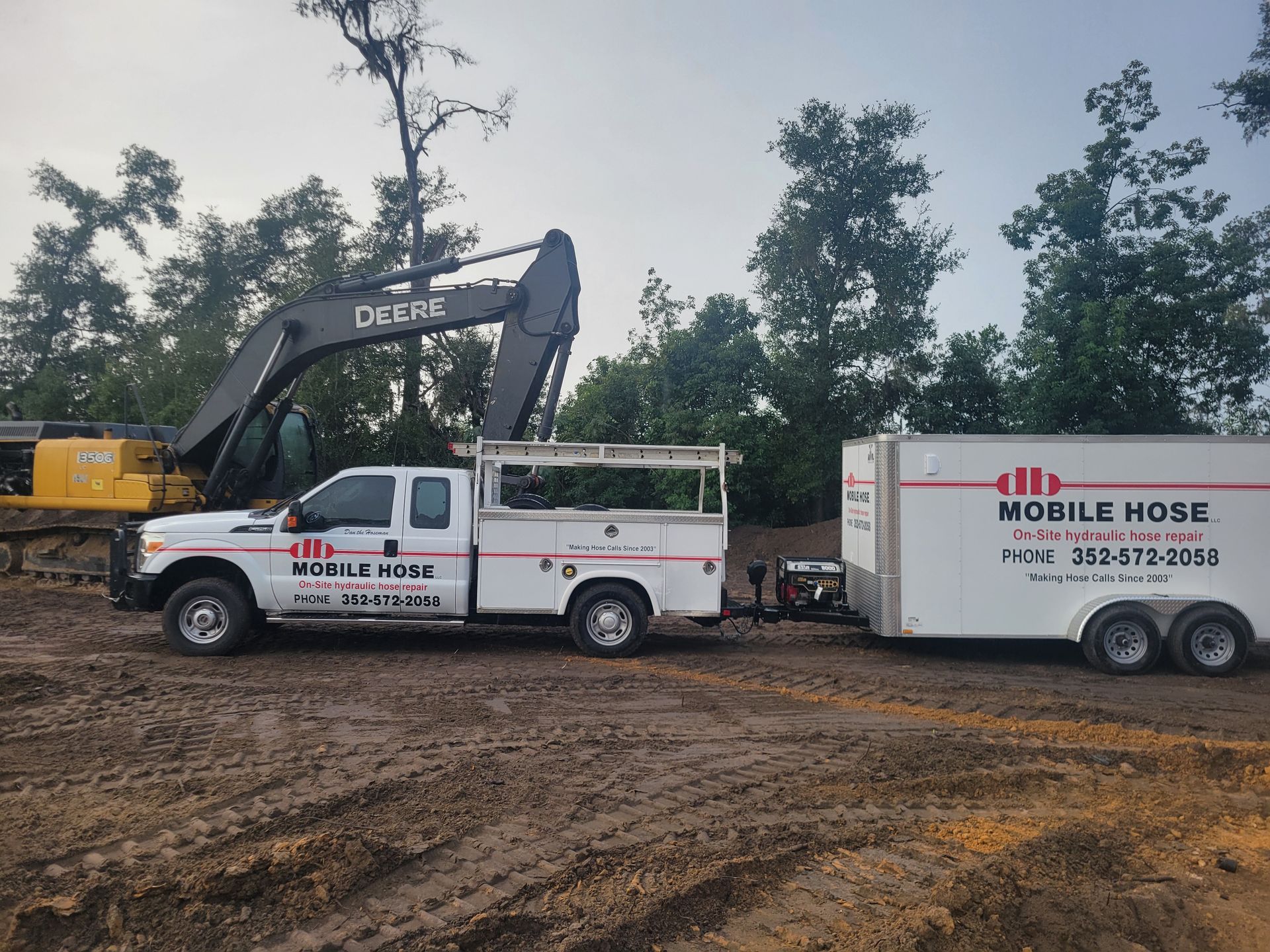 Orange forklift beside a white mobile repair trailer in a grassy area.