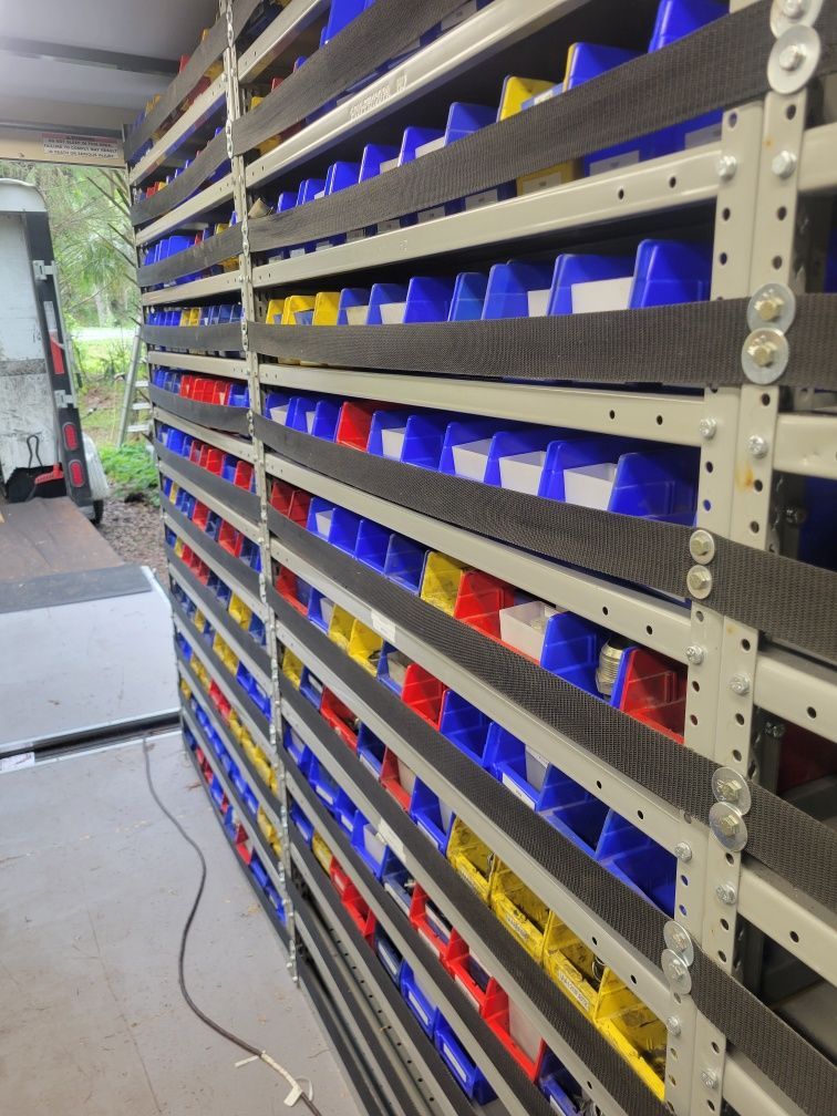 Shelving units filled with colorful bins inside a vehicle, likely for organizing parts.