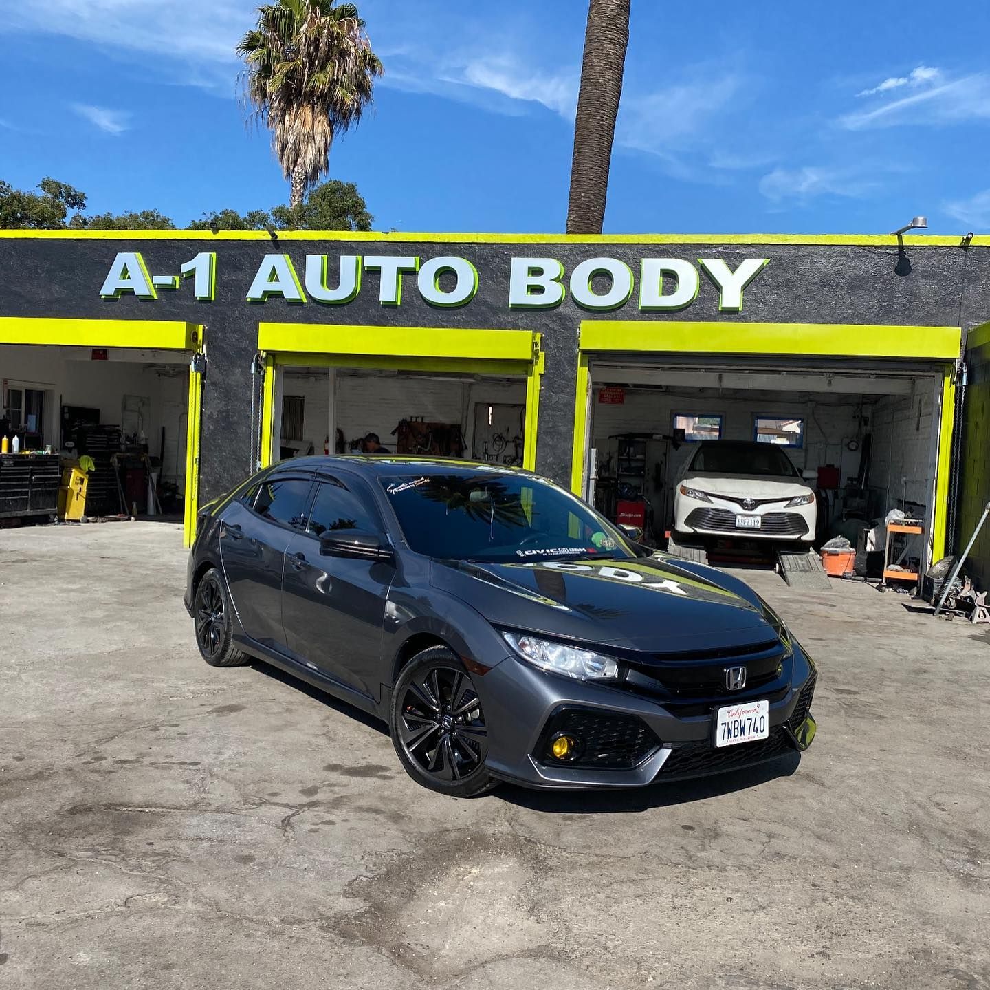A car is parked in front of a building that says a-1 auto body.