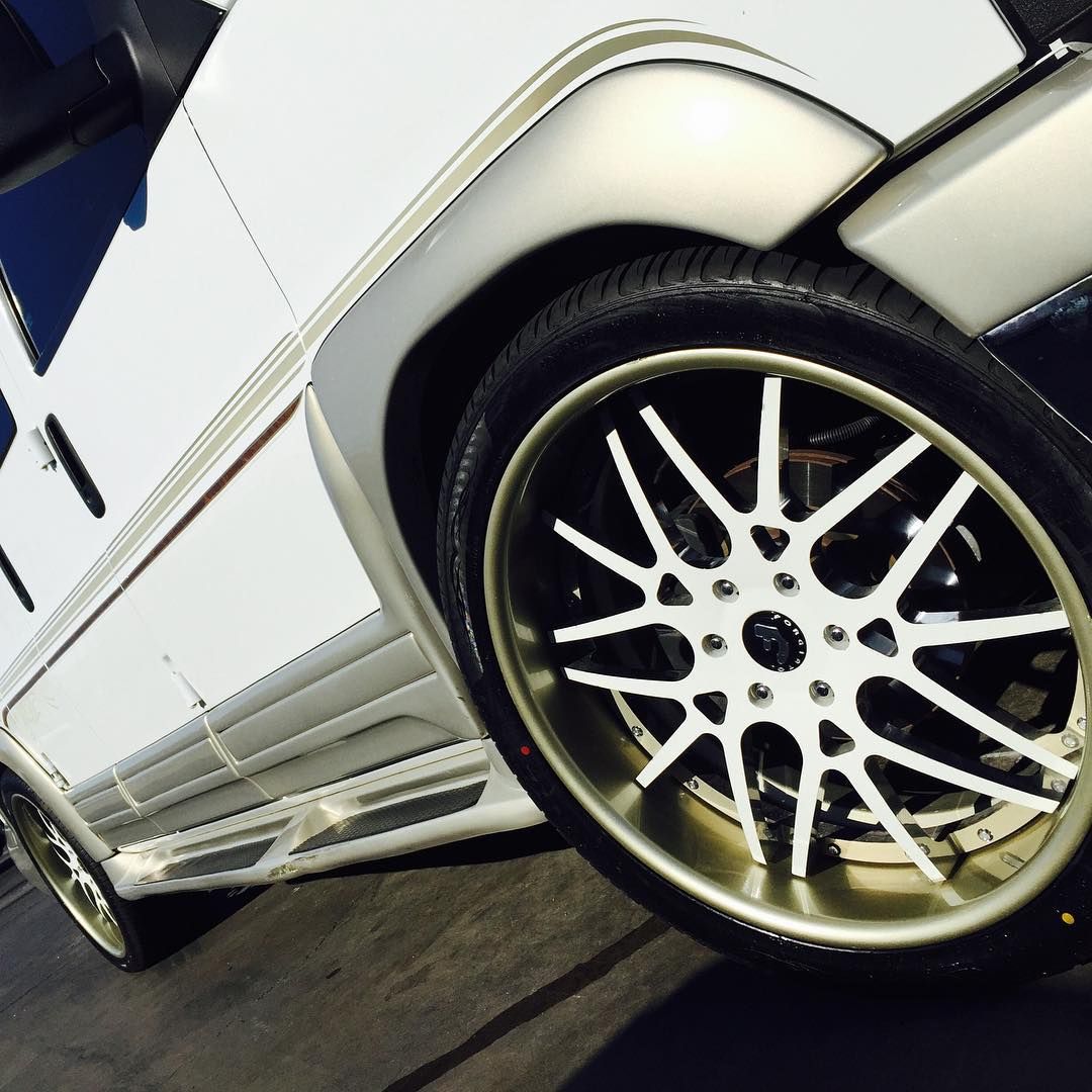 A white van with gold rims and a black tire