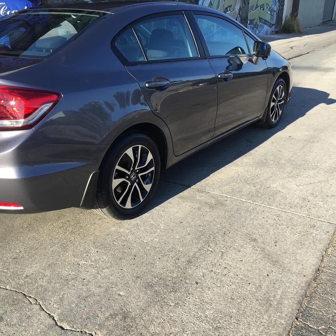 A gray car is parked on the side of the road