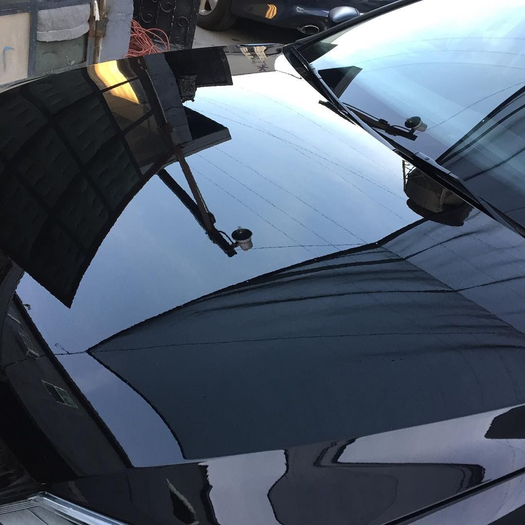 The hood of a black car is reflected in the windshield