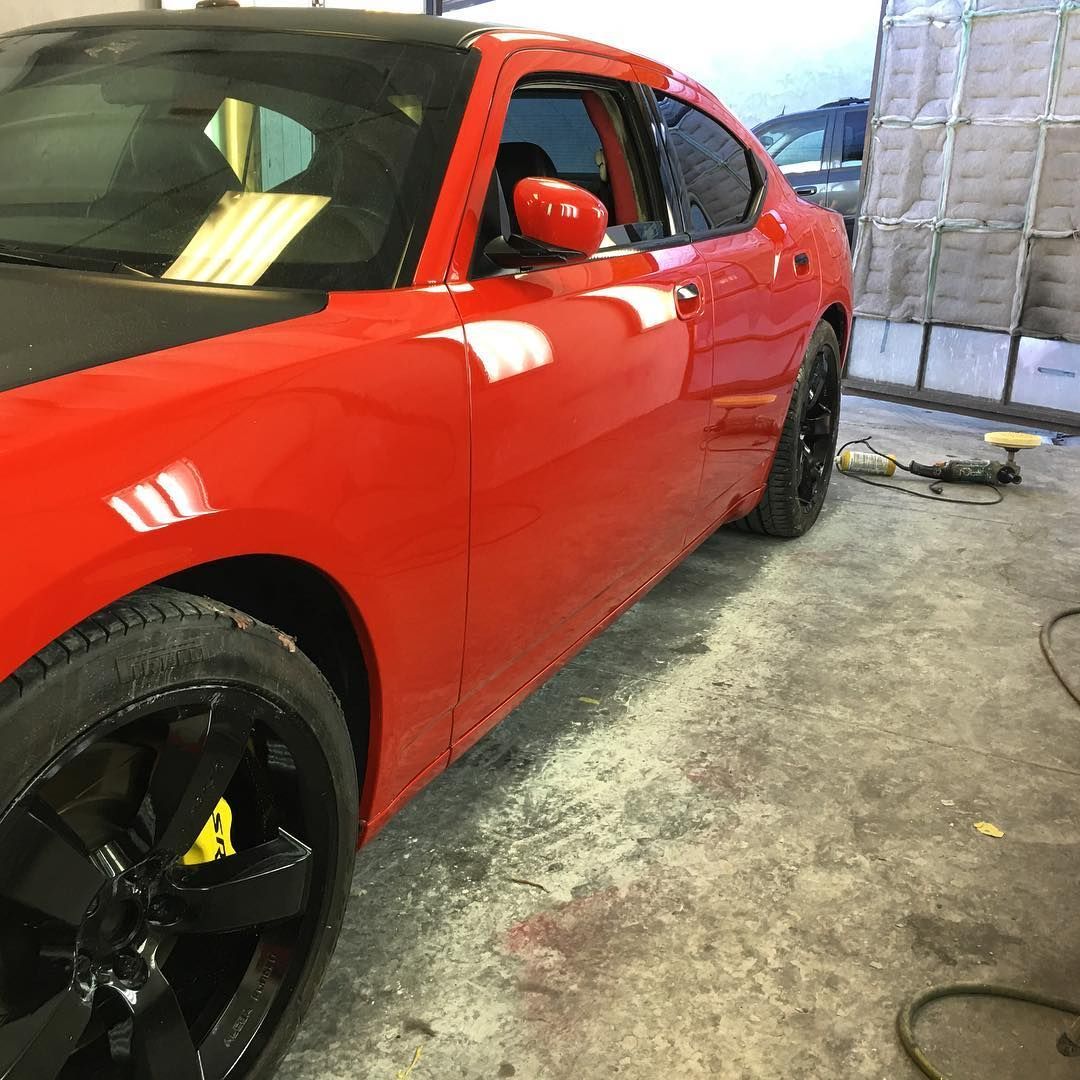 A red car with black wheels is parked in a garage.