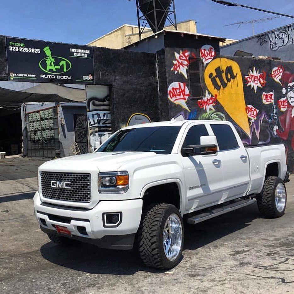 A white gmc truck is parked in front of a building with graffiti on it
