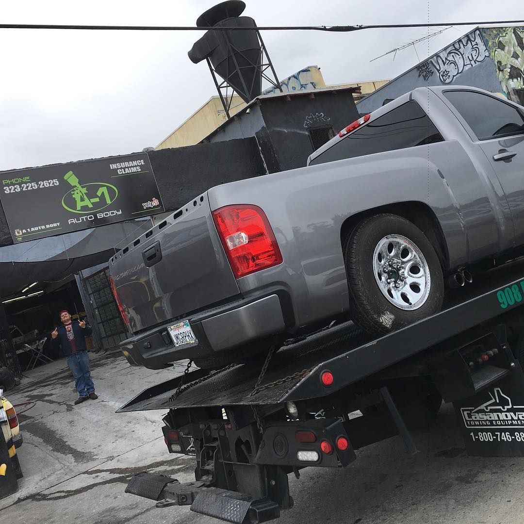 A gray truck is being towed by a tow truck.
