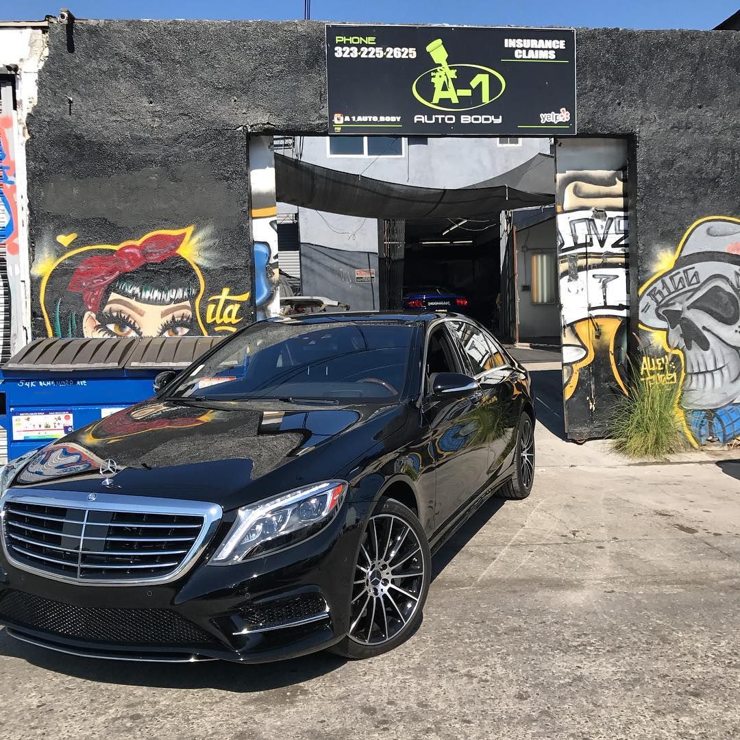 A black car is parked in front of a building with graffiti on it.
