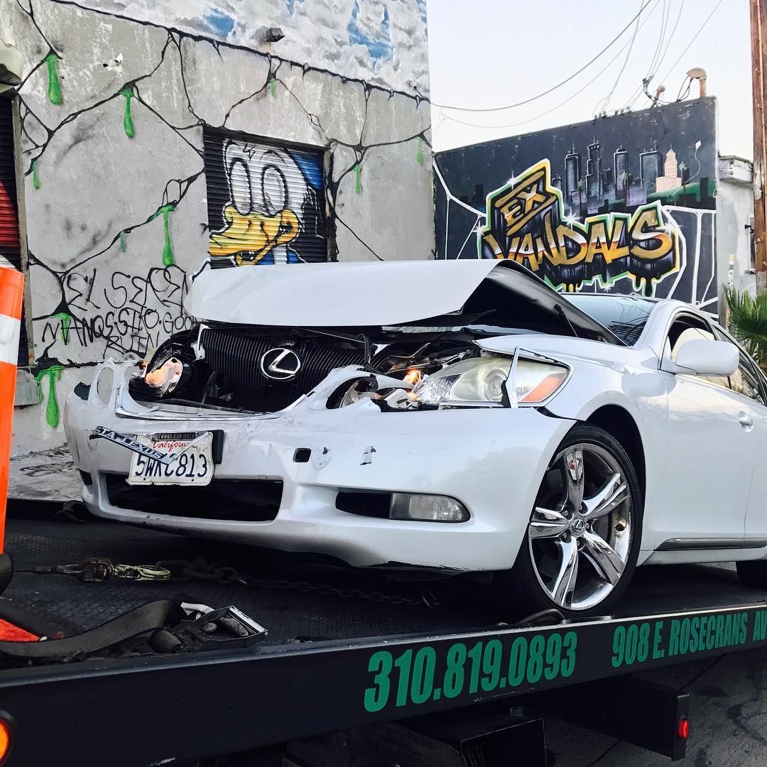 A white lexus is sitting on top of a tow truck