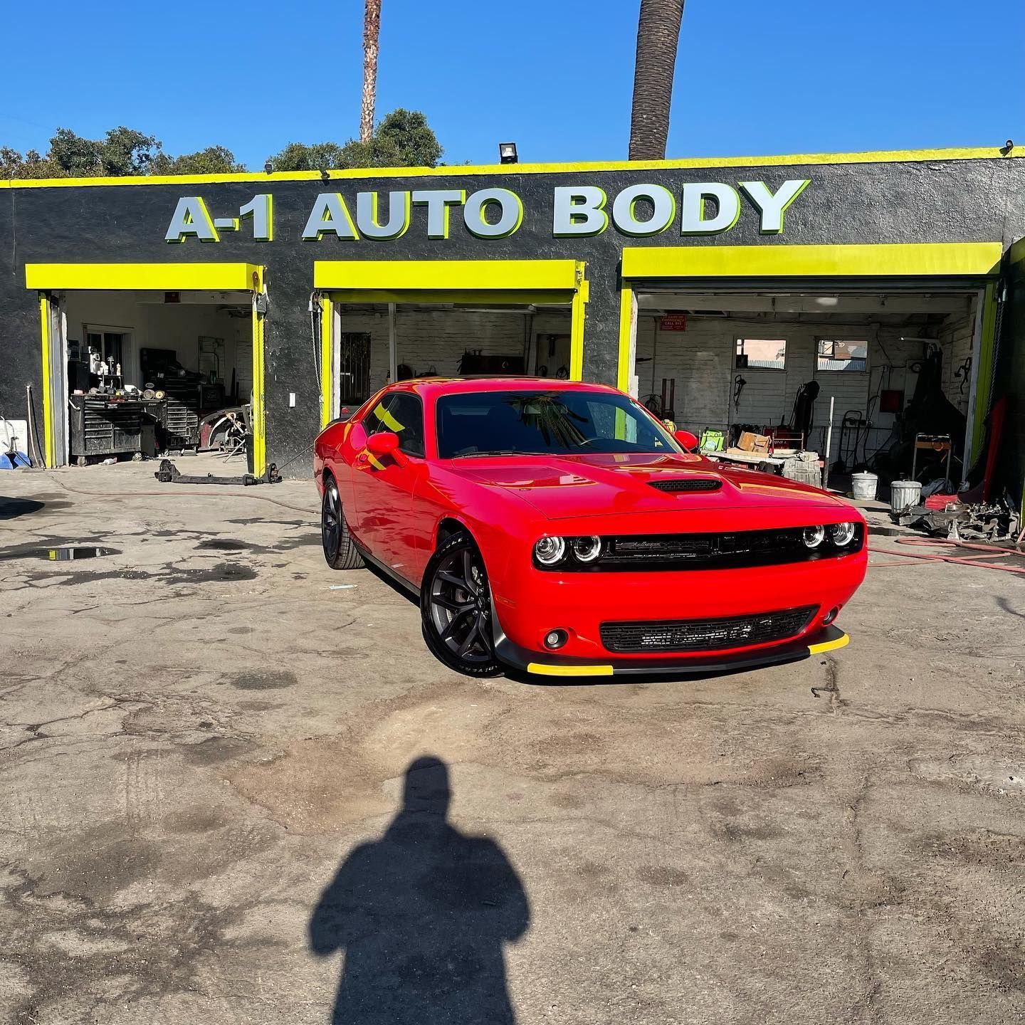 A red car is parked in front of a building that says a-1 auto body.