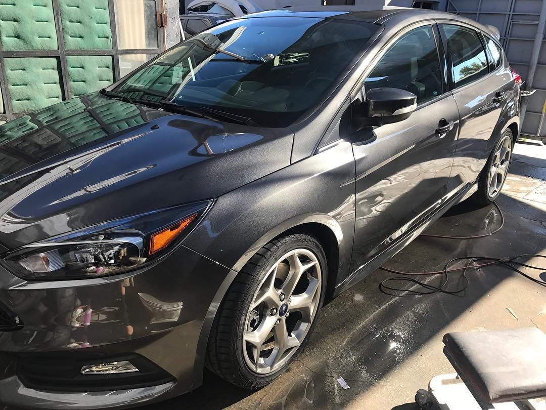 A gray ford focus is parked in a parking lot.
