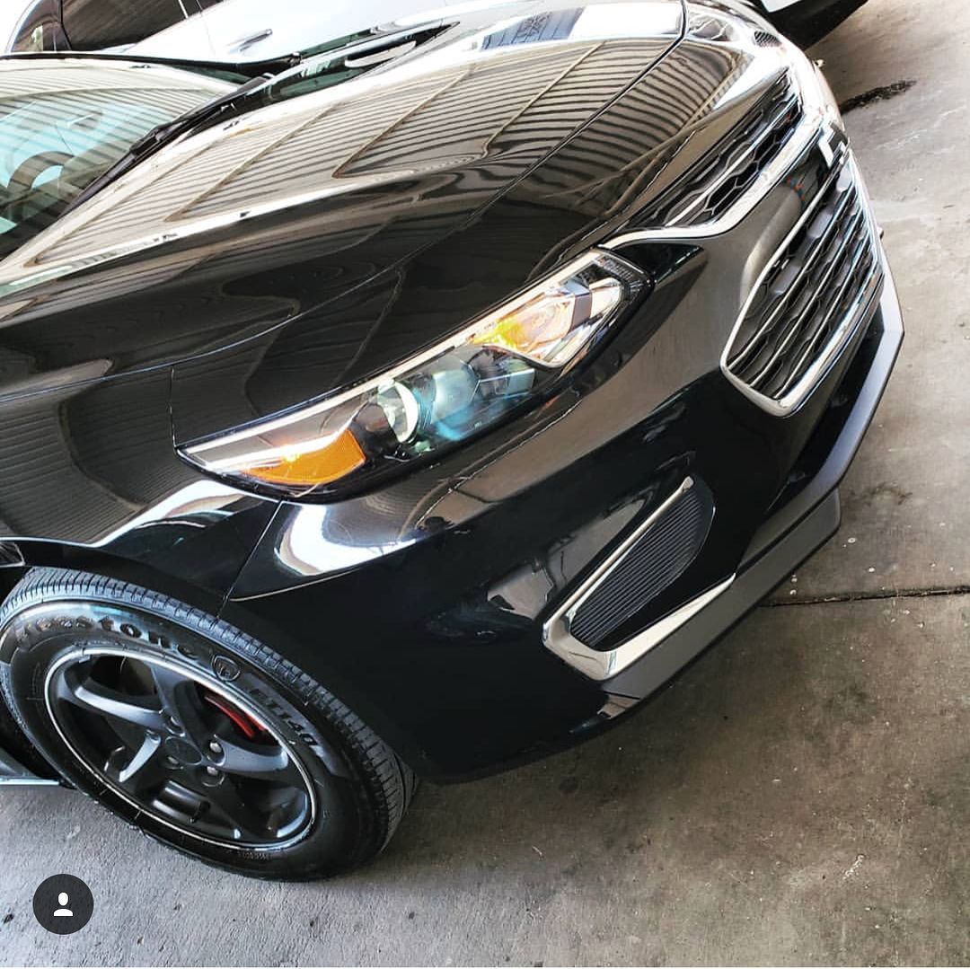 A black car with a yellow headlight is parked in a garage