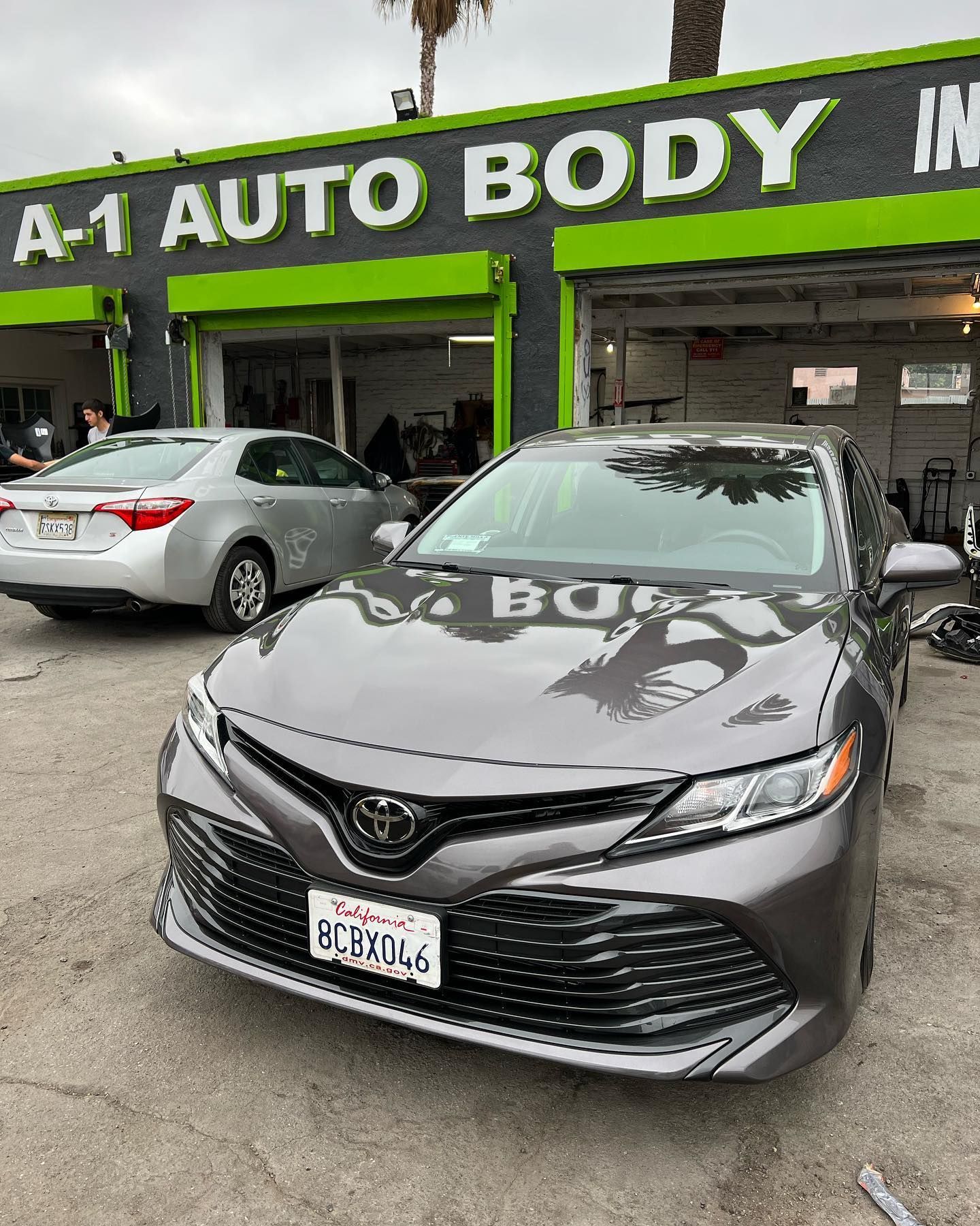 A toyota camry is parked in front of a car dealership.