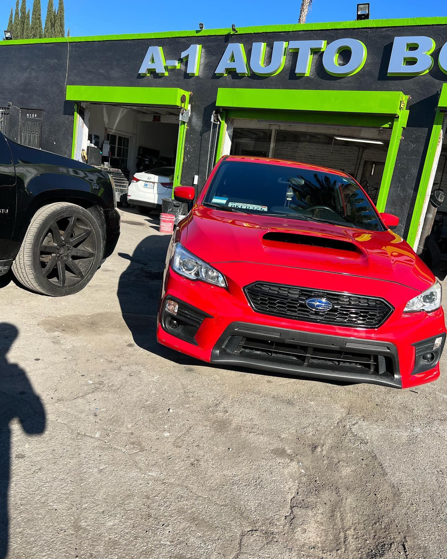 A red subaru wrx sti is parked in front of a car dealership.