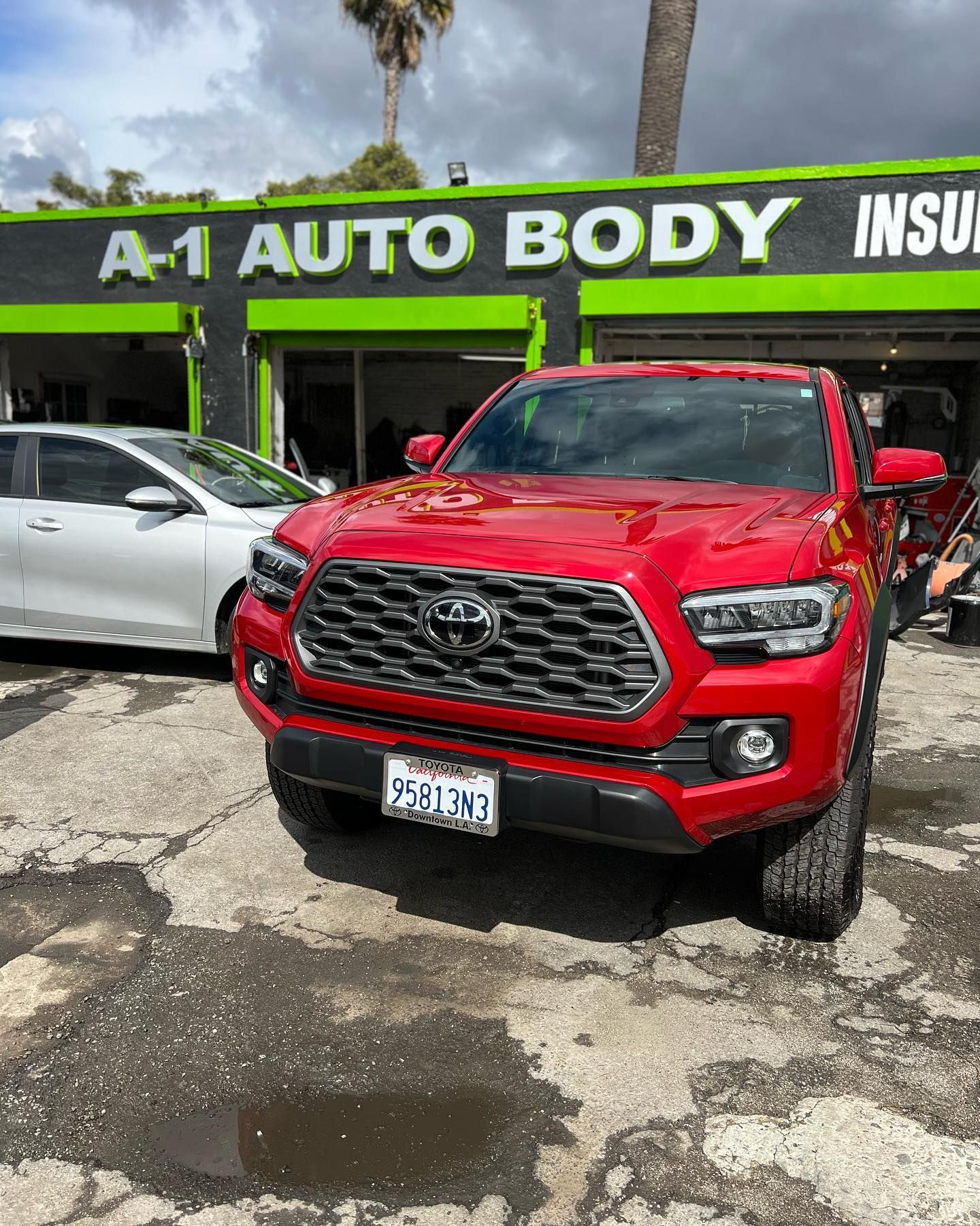 A red truck is parked in front of a car dealership.