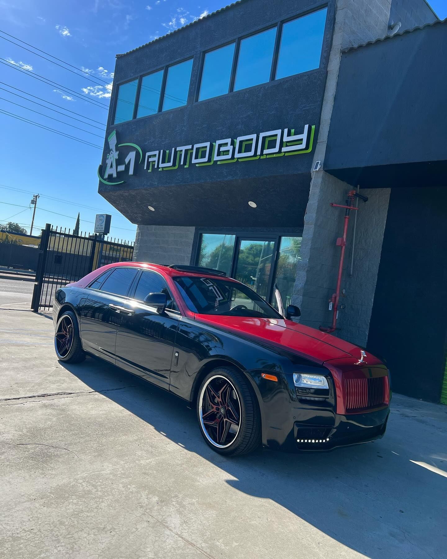 A black and red car is parked in front of a building.