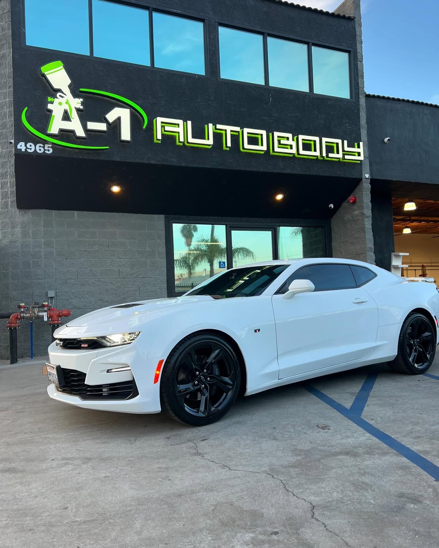 A white car is parked in front of a building.