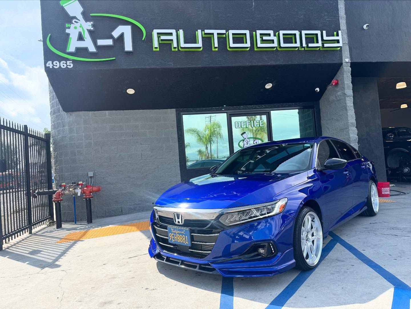 A blue honda accord is parked in front of a building.