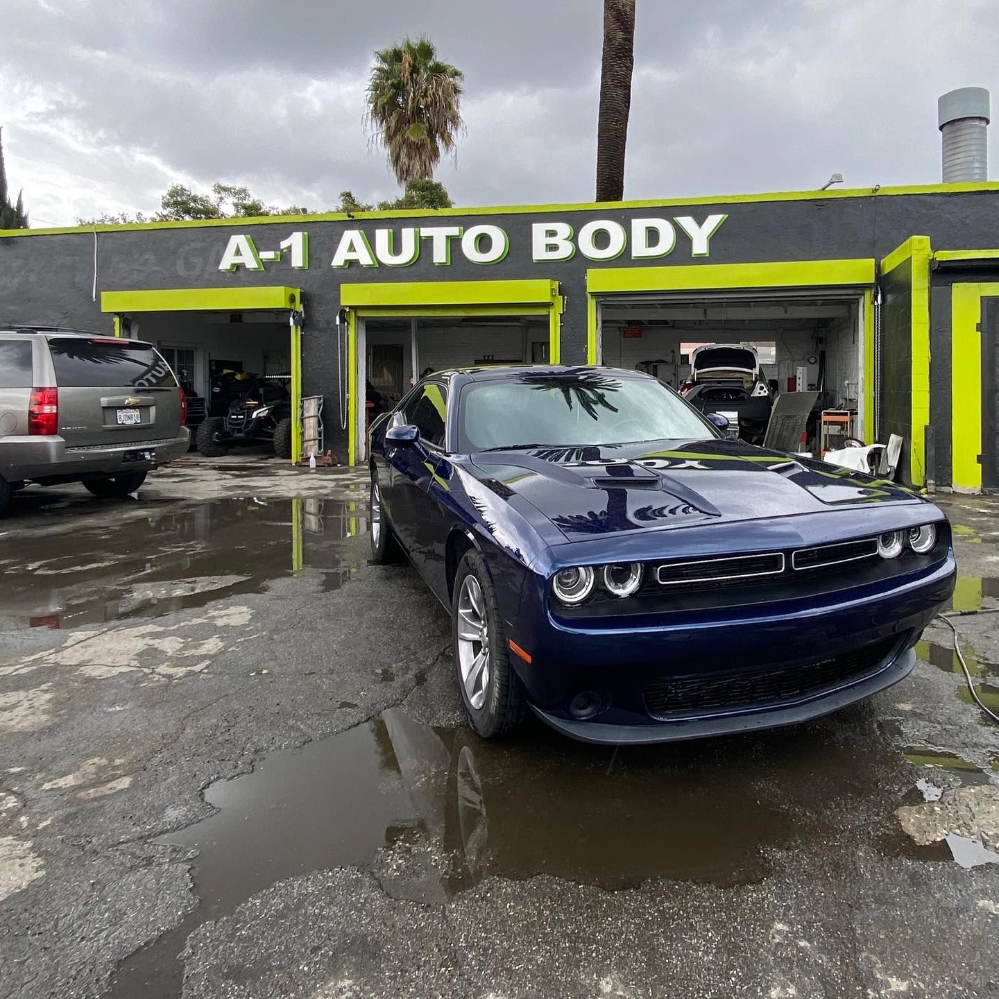 A blue car is parked in front of a building that says a-1 auto body