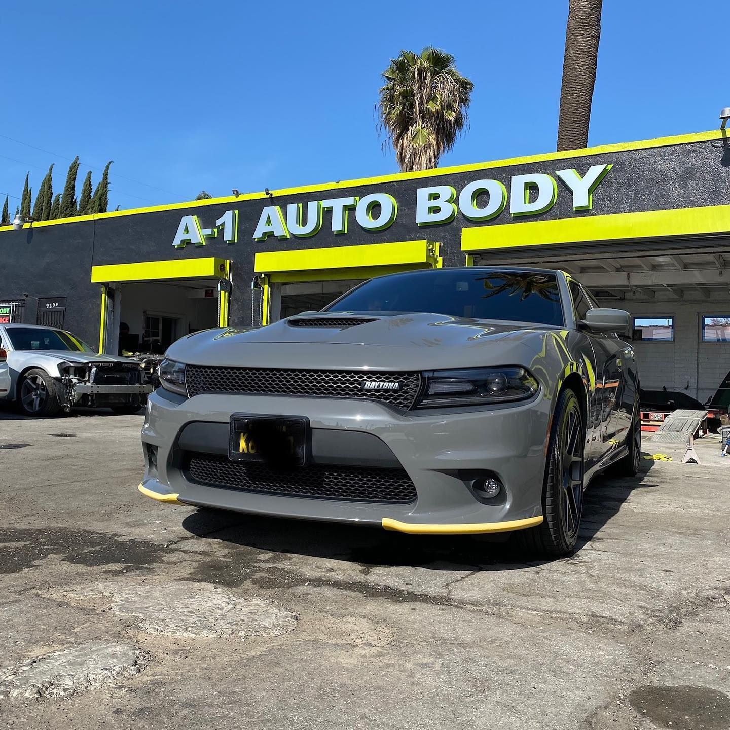 A gray dodge charger is parked in front of a car dealership.