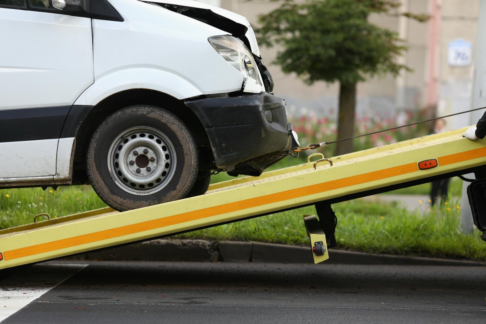 A white van is being towed by a tow truck.