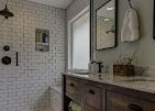 Bathroom with white brick tile shower, dark wood vanity, and a window.