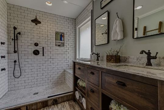 Bathroom with white subway tile shower, wood vanity, and two sinks.