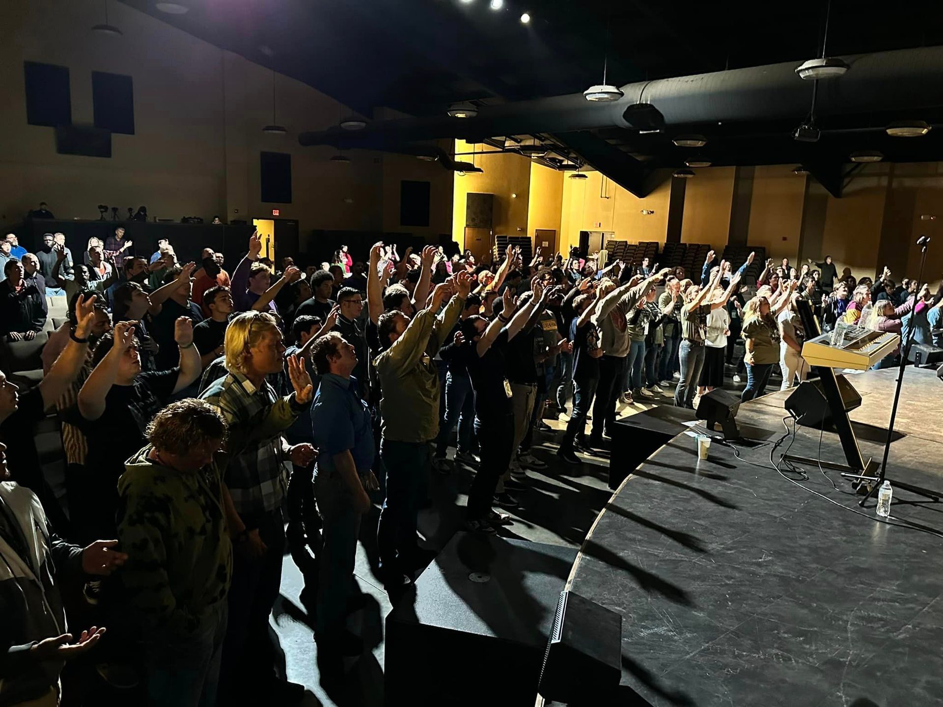 A large group of people are standing on a stage with their hands in the air.