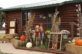 A log cabin decorated for fall with pumpkins and hay bales.