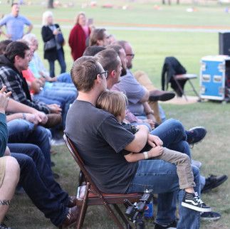 A group of people are sitting in chairs in a field.